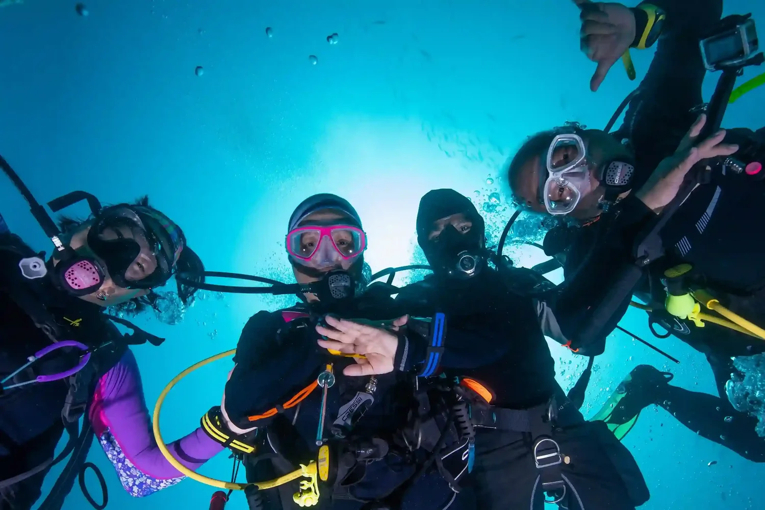 A group of divers descending through blue water